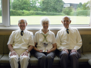 Senior Men and Senior Woman Sitting in a Lawn Bowling, Woman Holding a Trophy